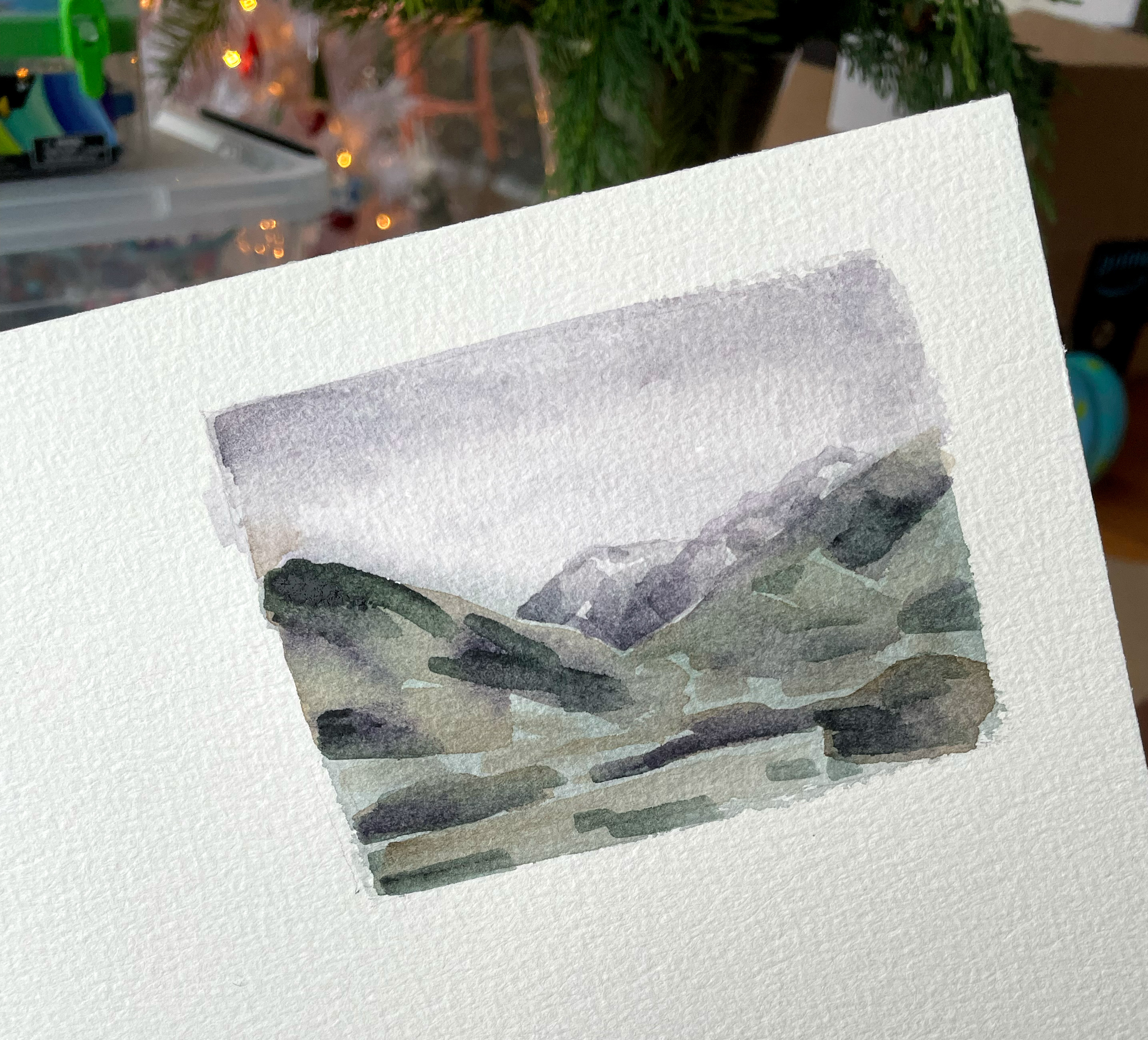 A small watercolor painting of a cloudy mountain view